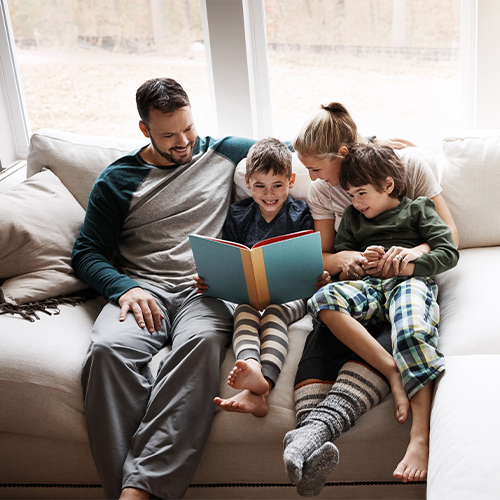 Family Sitting on a sofa reading a book.