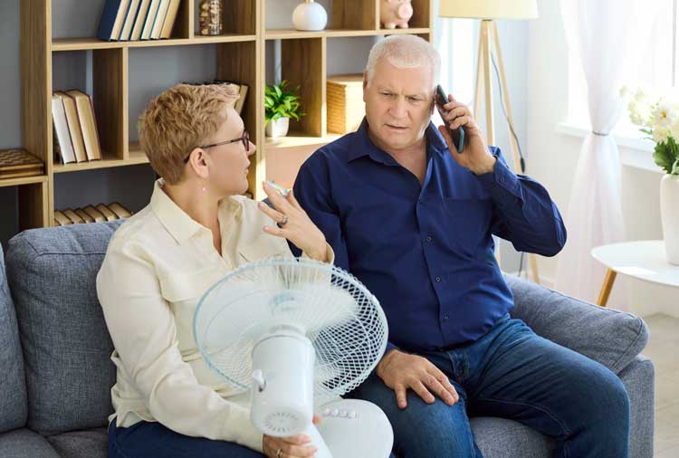 Couple sitting on a couch, while on the phone with an HVAC contractor