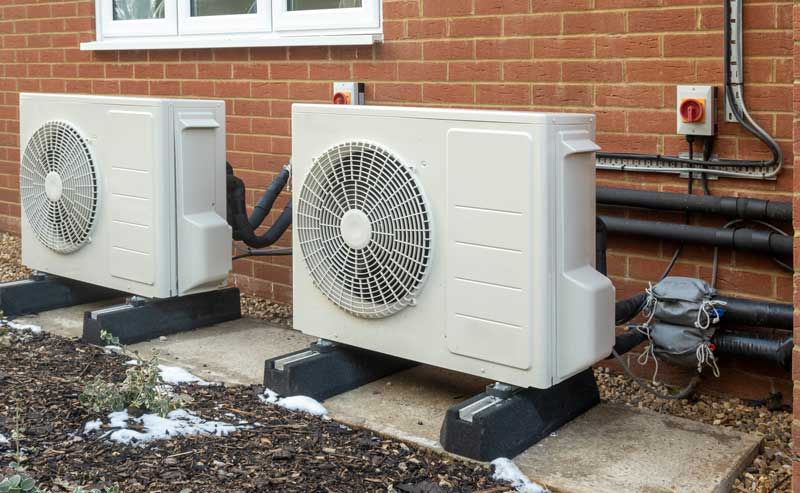 2 heat pumps sitting outside a home.